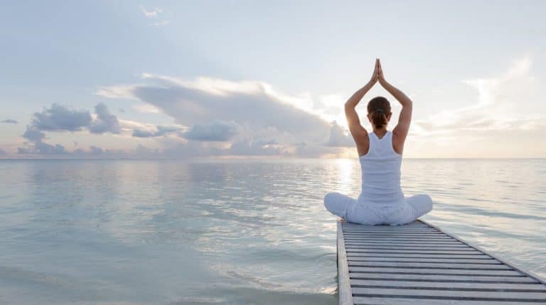 Femme qui pratique sa sadhana quotidienne sur la plage