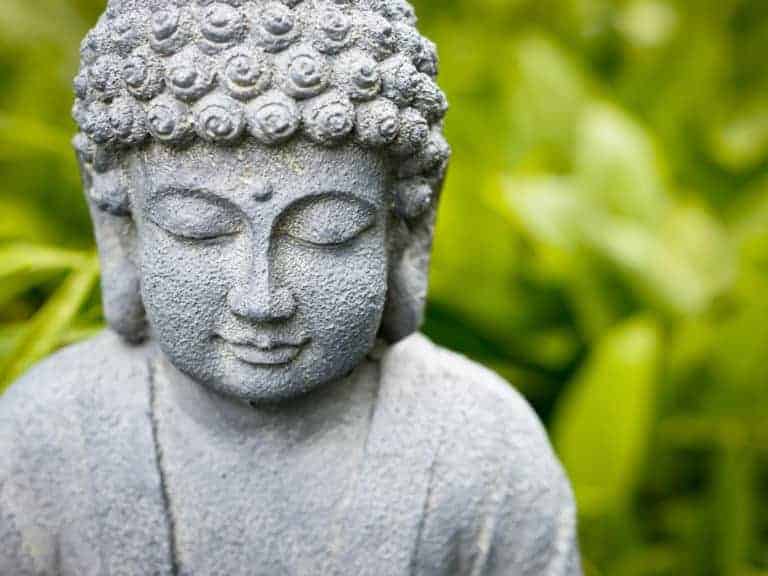 Un Bouddha souriant qui médite dans l'herbe.