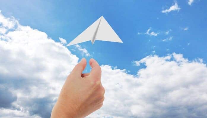 envoi d'un avion en papier dans le ciel avec des nuages