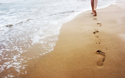 quelqu'un qui laisse ses traces de pas dans le sable, sur la plage au bord de l'eau